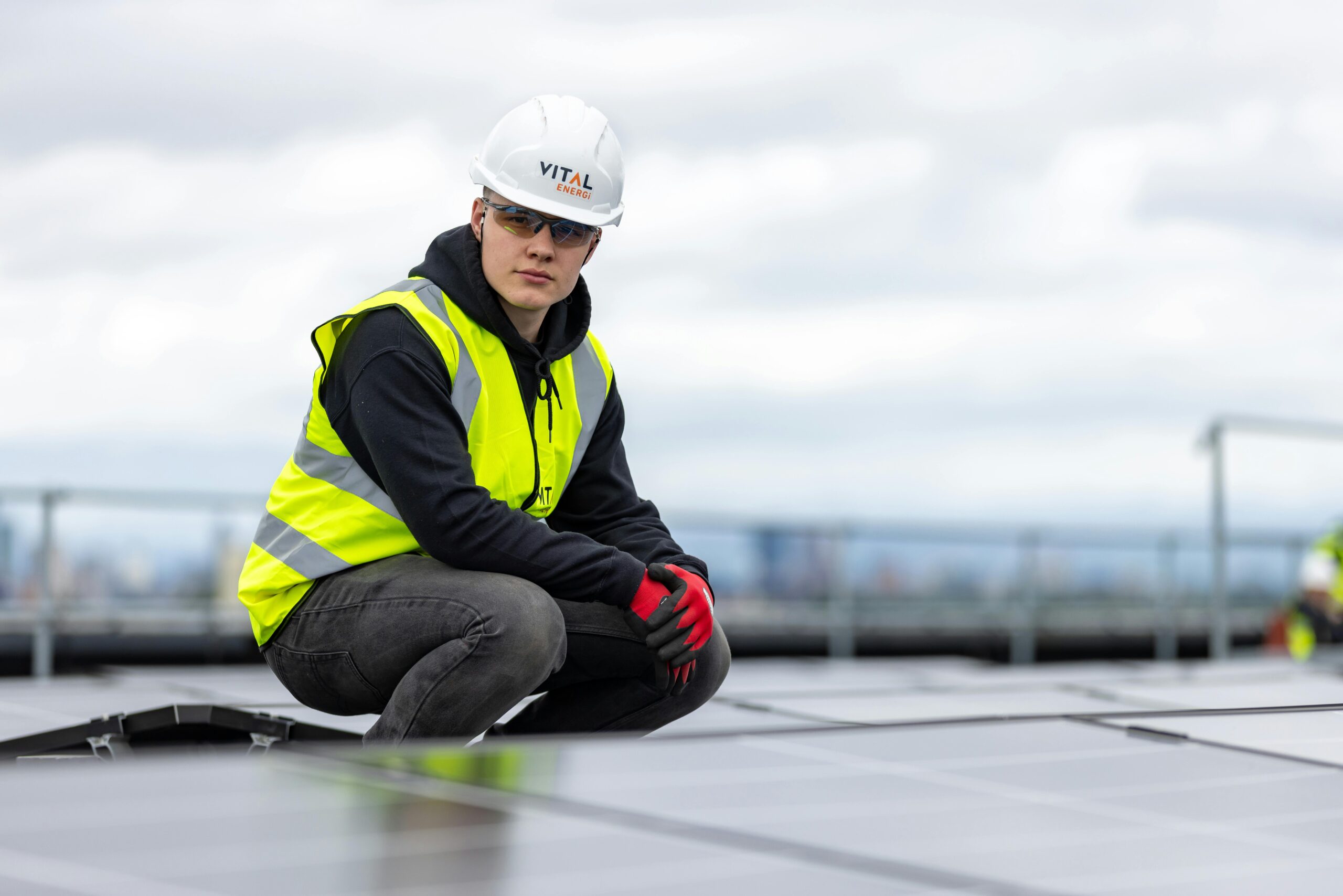 Solar panel installer checking rooftop solar panels on a residential home under bright sunlight